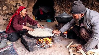 (ویدئو) روش دیدنی یک زوج غارنشین افغان در پخت نان و یک غذای محلی با گوشت و لوبیا