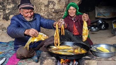 (ویدئو) روش دیدنی یک زوج غارنشین افغان در پخت یک غذای محلی با ماهی