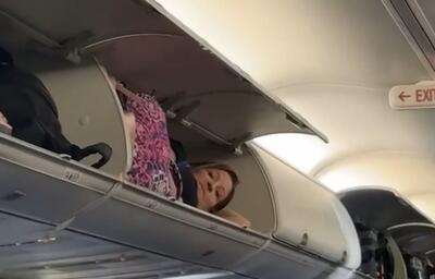 (ویدئو) خوابیدن یک زن در محفظه بالای سر مسافران هواپیما!