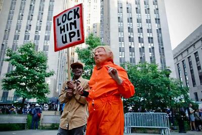 ترامپ با لباس زندانی در خیابان‌های آمریکا پلاکارد به دست!