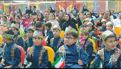 پرچم سه‌رنگ ایران در میان میدان مدرسه با لبخند کلاس اولی‌ها