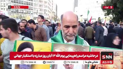  مردی با در دست داشتن تصاویر شهدای مقاومت در گفتگو با SNNTV: جای شهدا و دانشمندان هسته‌ای در راهپیمایی امروز خالی است / آمریکا دم از حقوق بشر می‌زند اما کودک یک ماهه را به شهادت می‌رساند