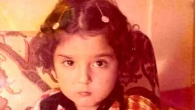  آیا میدانید این دختر کوچولو بامزه با لباس چارخونه و گیره‌های روی سرش بچگی کدوم بازیگر معروف هست؟ / باور نمیکنید!