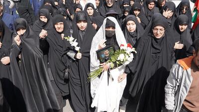  همسر شهید محمد نقوی با چادر سفید و گل به بدرقه همسرش آمد
