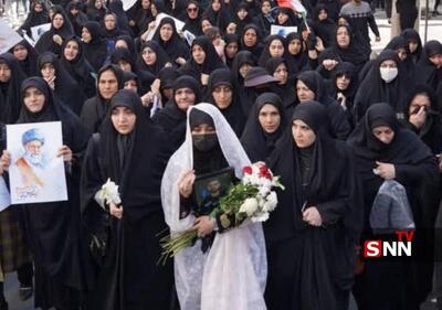  همسر شهید محمد نقوی با چادر سفید و گل به بدرقه همسرش آمد