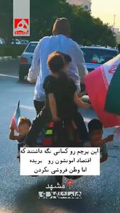  تصویر وایرال شده از ۲ کودک پرچم به دست در خورجین دوچرخه پدر! + فیلم